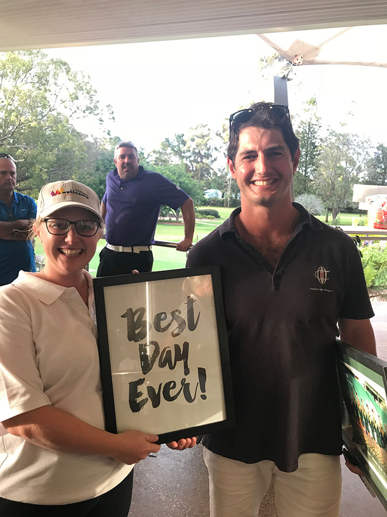 A couple holds a "Best Day Ever!" sign at a Golf Day to raise Epilepsy Awareness